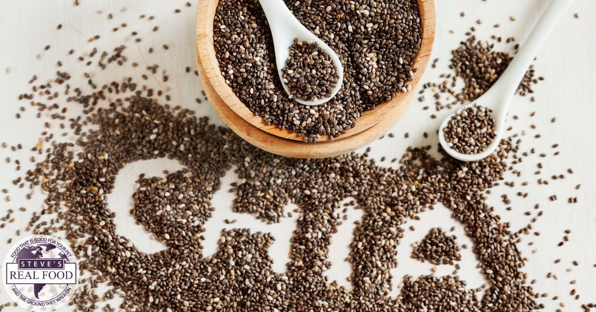 Chia seeds in a bowl and two spoons with seeds also scattered on a table