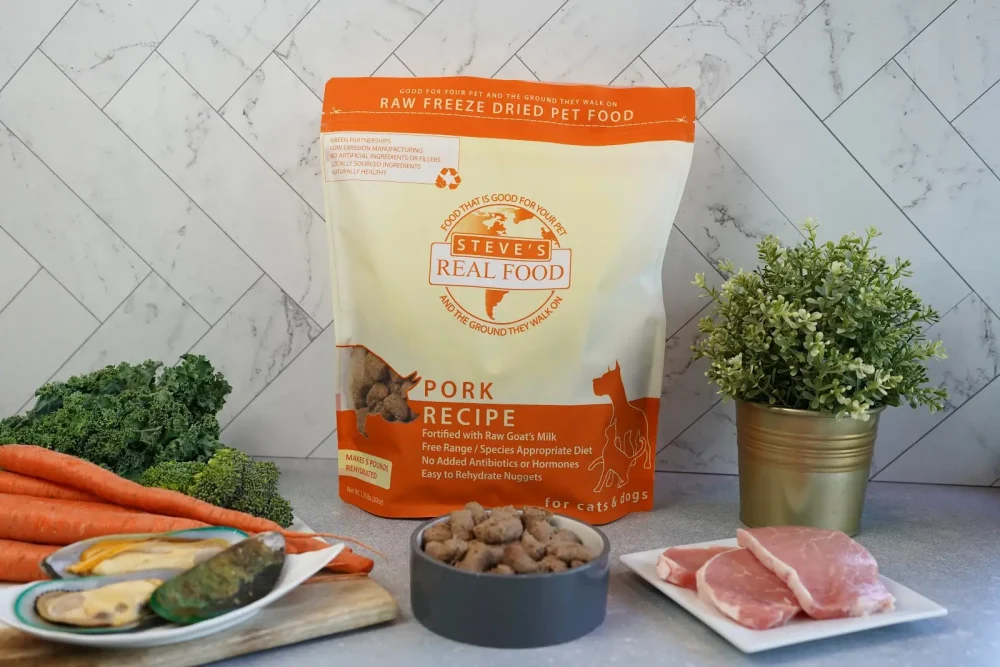 Front of bag of Raw Freeze Dried Pet Food Pork Recipe on counter with port and vegetables